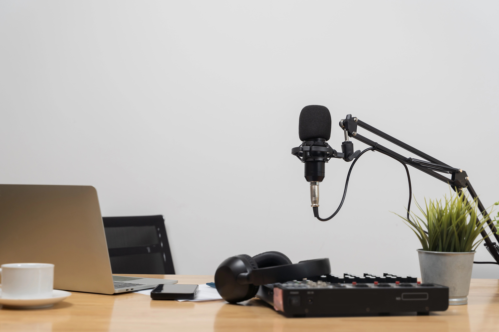 A podcast setup with a microphone clamped to a desk next to a laptop